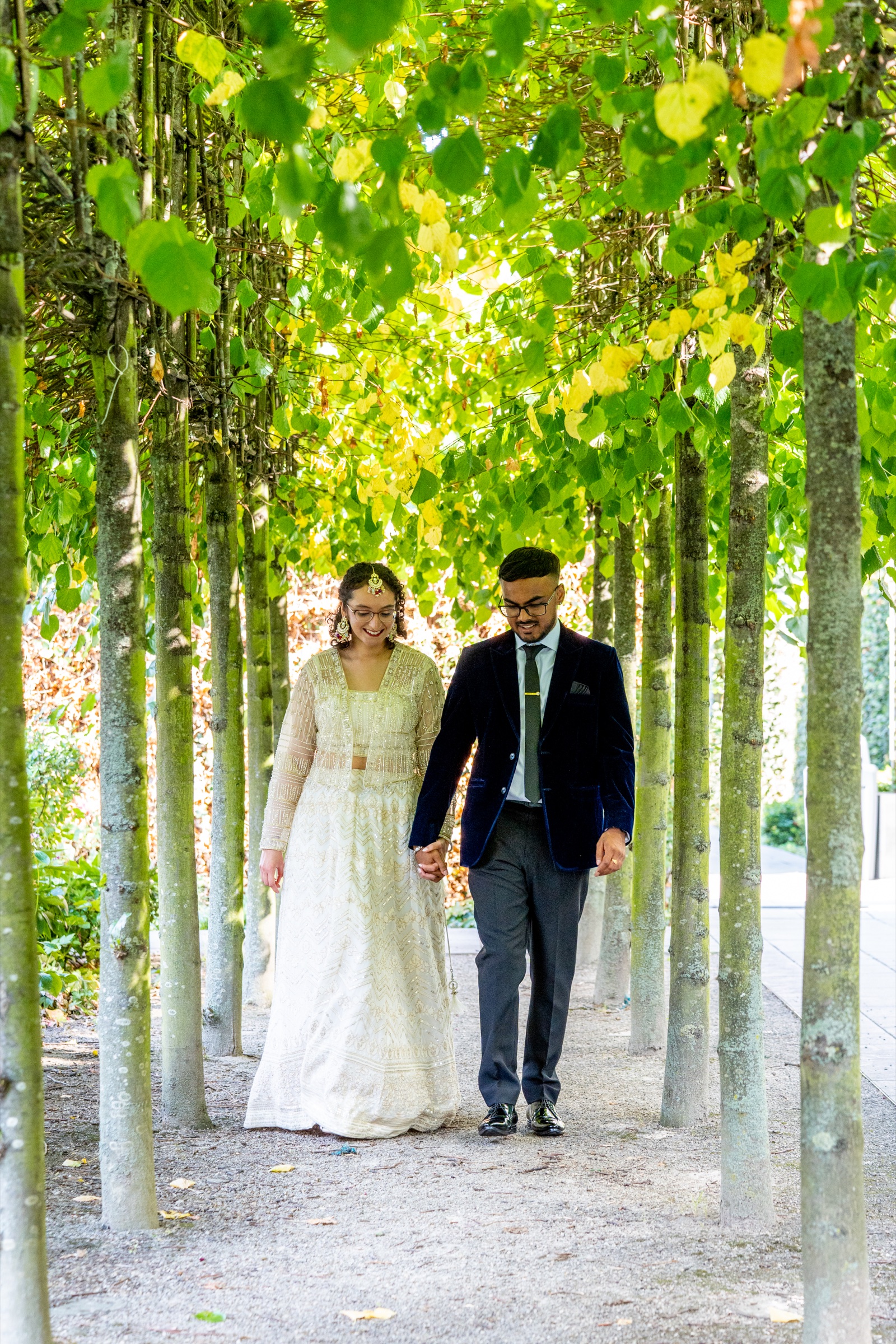 A couple walking beneath a canopy of leaves