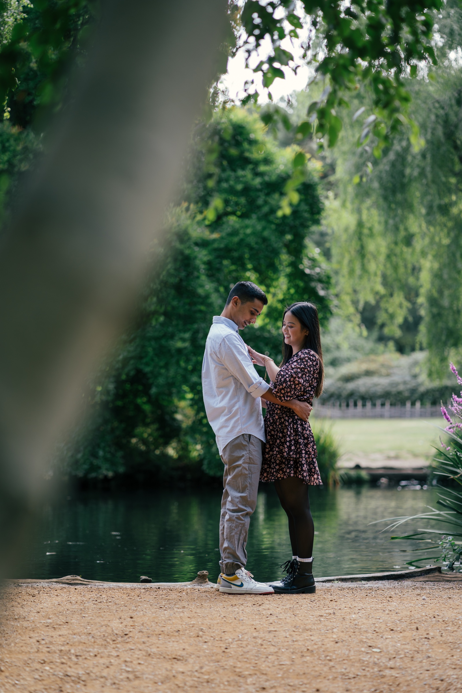 A couple sharing a quiet proposal moment beside a lake